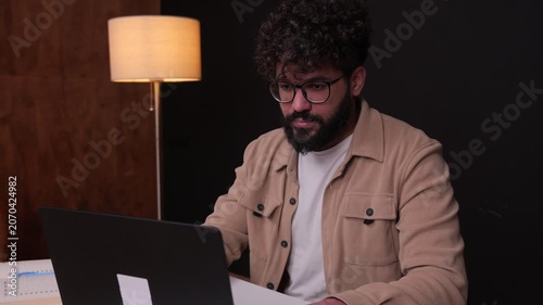 Focused young professional man working on laptop computer at night