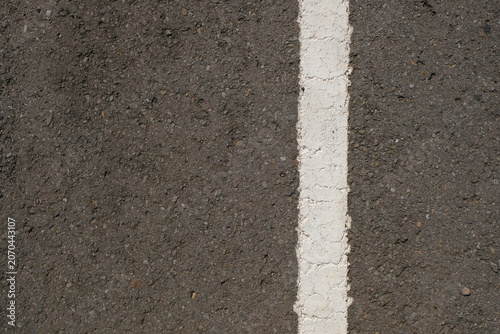 Fotografie Close-up of asphalt pavement texture with a cracked white dividing line