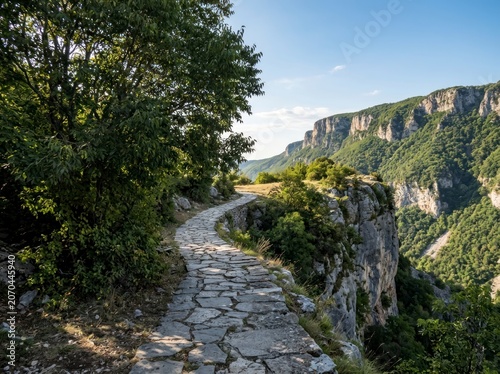 Stone path along a cliff edge, scenic mountain valley landscape.
