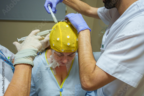 Medical professionals fitting an eeg cap and electrodes to ready a patient for brain activity monitoring