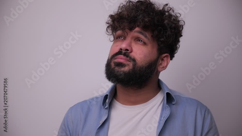 Thoughtful bearded man with curly hair thinking about a problem
