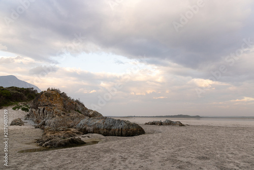 low tide at rocky coastline of Grotto Beach, Hermanus, South Africa at dusk
