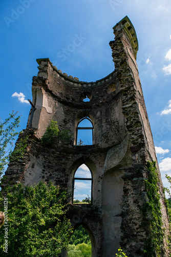 Ancient castle tower ruins at Chervonograd in Ukraine surrounded by dense greenery, showcasing centuries of history under sunny skies.