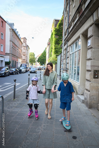 Mother and children enjoy a sunny day with outdoor activities on a city street
