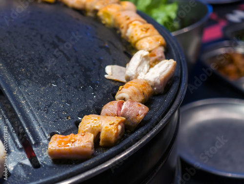 Grilled Meat on a Korean BBQ Grill with Fresh Vegetables and Side Dishes