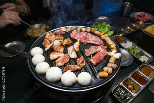 Grilled Meat and Vegetables on Korean BBQ Grill with Smoke and Sides
