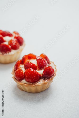 Canvastavla Two strawberry tartlets with cream filling on a white surface