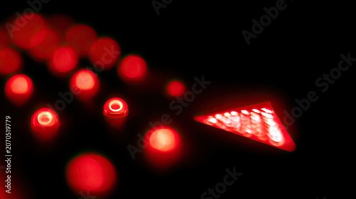 Blurred red lights glow, leading to a sharp, illuminated triangular arrow