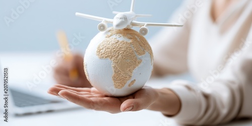 Airplane model resting on a globe held in a person's hand