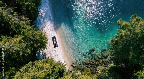 Aerial view of serene beach, person on mat, clear turquoise water