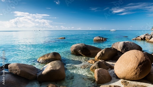 Large Stones On The Seashore Calm Water And Blue Sky