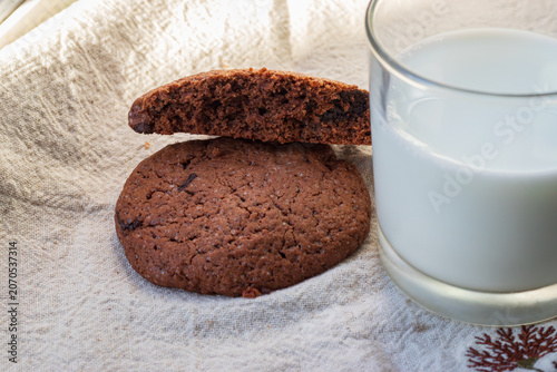 Fotografie Chocolate chip cookies and a glass of milk on a linen tea-towel