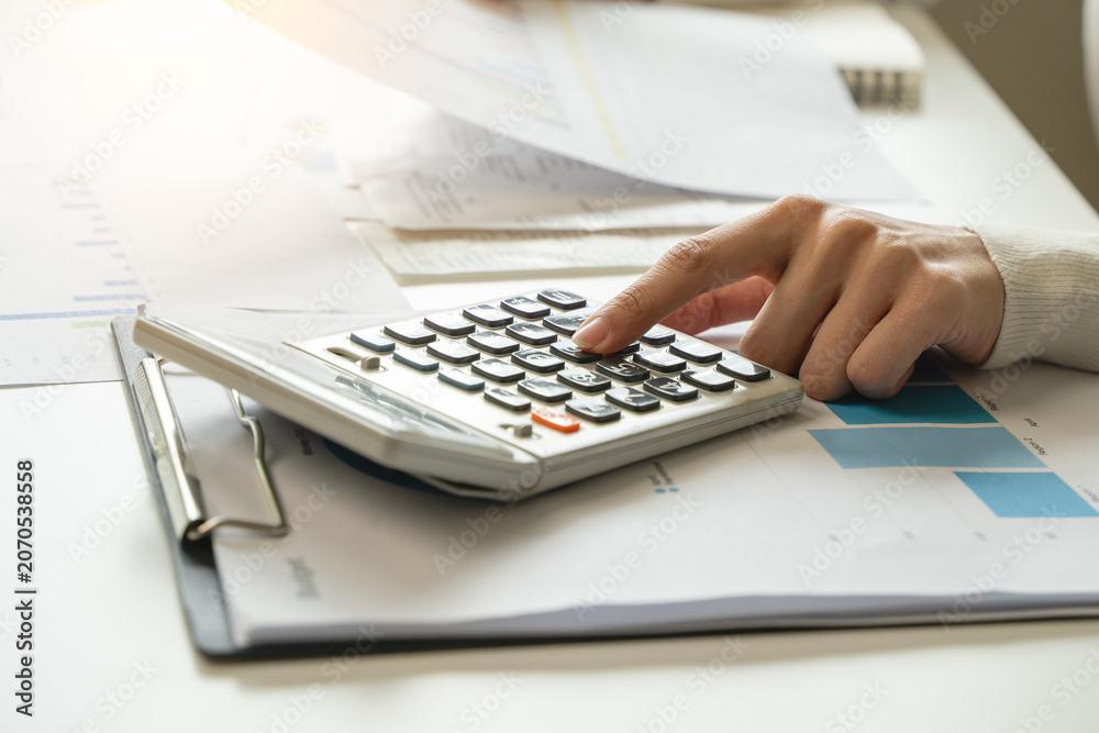 Fototapeta premium Women business people use calculators to calculate the company budget and income reports on the desk in the office.