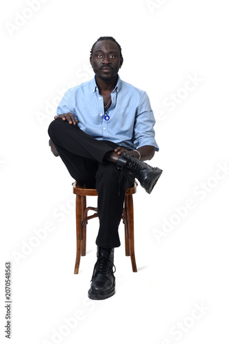 front view of a man sitting on chair looking at camera and cross legged  on white background