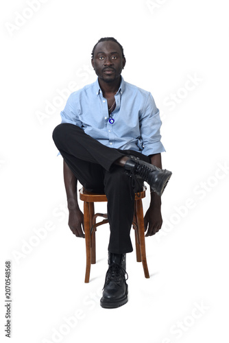 front view of a man sitting on chair looking at camera and cross legged  on white background