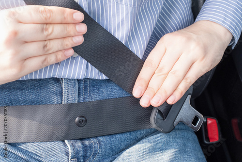 Female hand fastens the seat belt in the car close-up.