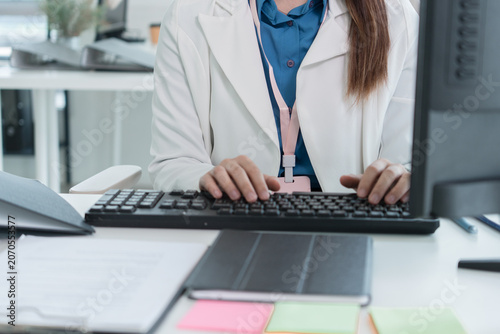 Young Businesswoman Working at Office Desk While Managing Documents and Mobile Communication.