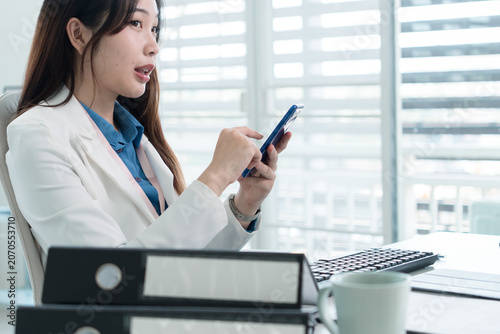 Young Businesswoman Working at Office Desk While Managing Documents and Mobile Communication.