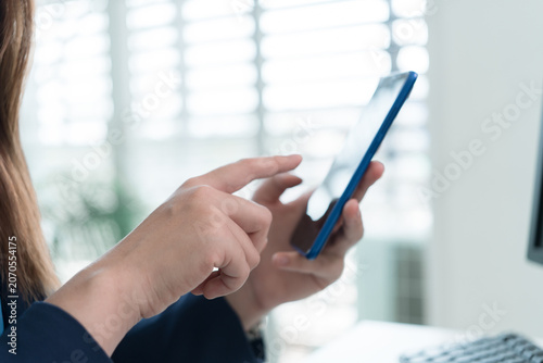 Young Businesswoman Working at Office Desk While Managing Documents and Mobile Communication.