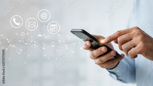 Businessman using a modern smartphone to access digital communication channels and professional networking connectivity icons