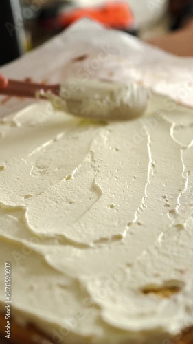 Baking at home, close up of spreading cream on cake sheet for homemade Swiss roll