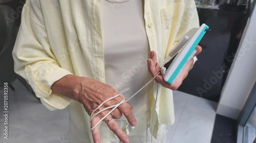 Woman secures cleaning tool by wrapping cord on hand. Reliable protection measures keep cleaning tool safe from sudden high fall, making magnetic window washing process calm and completely risk-free.