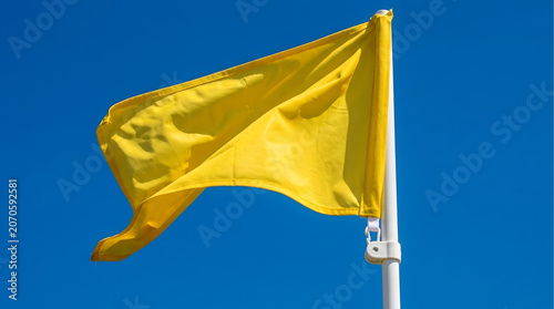 Yellow Flag Waving Against Clear Blue Sky.