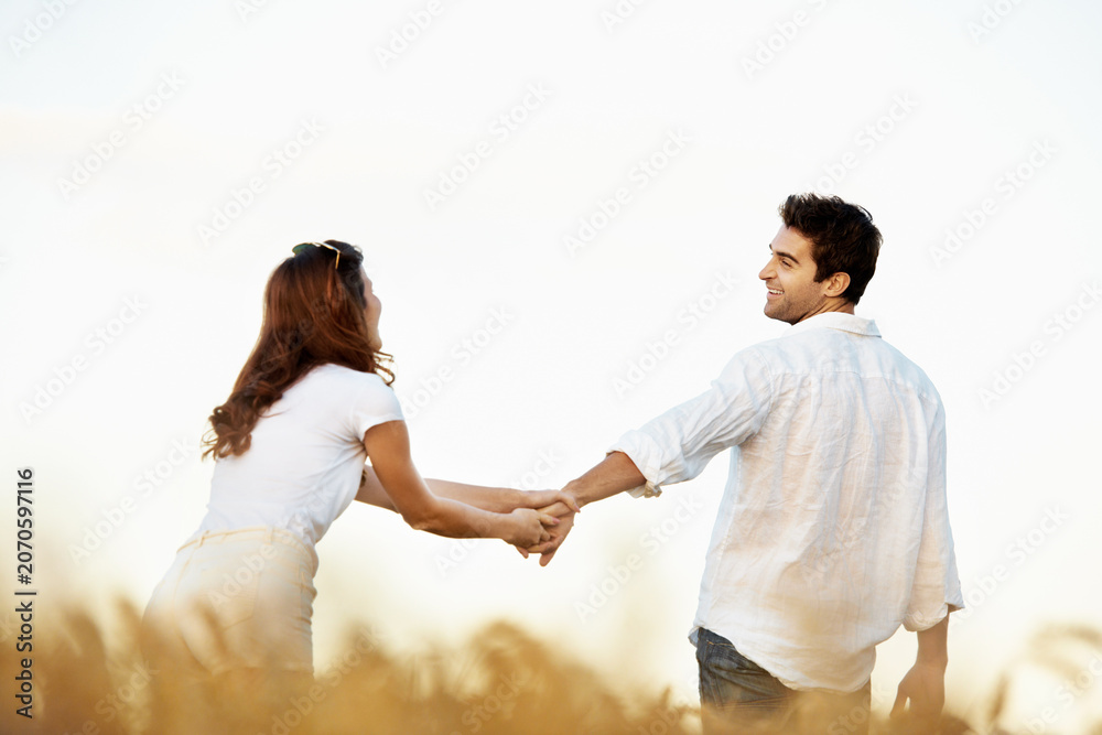 Obraz premium Couple, happiness and man holding hands in meadow, partner and support with care in nature. Male person, smile and woman outdoor for relationship, bonding and together with love, space and walk