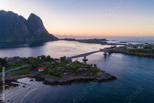 Tableau sur toile Aerial dusk view shows a slender bridge linking rocky islets near Reine and Reinebringen in Lofoten, Norway