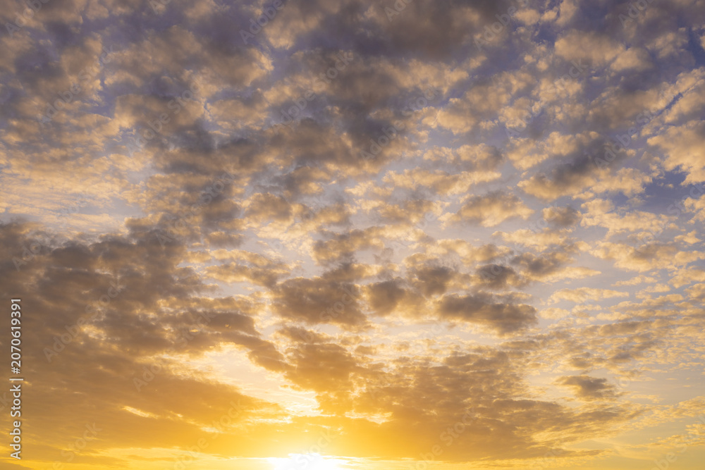 Fototapeta premium Golden sunset sky with soft scattered clouds,A breathtaking view of the golden sunset sky featuring soft, scattered clouds illuminated by the warm light of the setting sun, creating a peaceful.