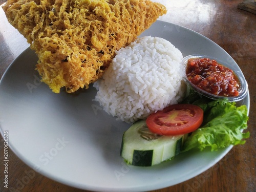 Crispy Fried Chicken with Rice and Sambal on wooden table.
