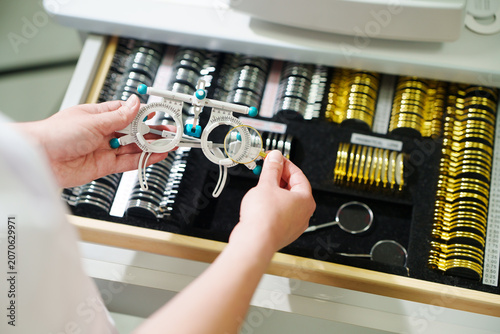 High angle view of doctor choosing trial frame from medical case