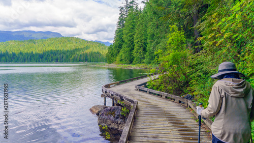 Fotografía Senior female hiking on lakeside boardwalk on Sasamat Loop trail in Belcarra Provincial Park, BC, Canada