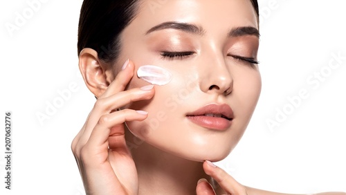 Elegant woman applying luxury skincare cream on face with soft studio lighting on clean white background