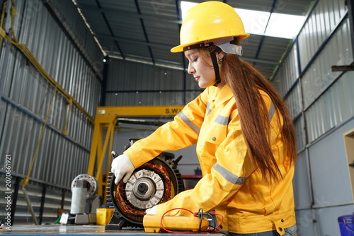 Female Industrial Technician Inspecting Electric Motor in Manufacturing Workshop
