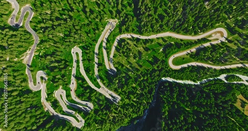 Establishing shot of cars on road trip across the mountains of Switzerland drive along hairpin turns. Aerial drone view winding mountain road