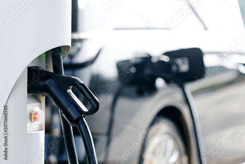 Canvas-taulu Electric car vehicle plugged into Fast charger charging station at curbside