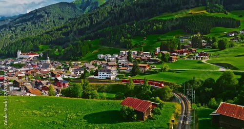 Establishing shot of Switzerland. Aerial view of the green meadows of Switzerland, with the Alps and clouds in the background