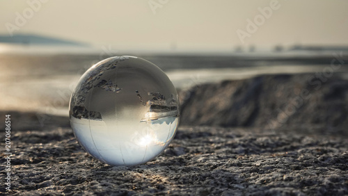 Cuadro en lienzo A Crystal ball, Earth, Globe, world, glass ball placed on a rock beach, reflecting an inverted seascape and horizon with sunlight in the morning