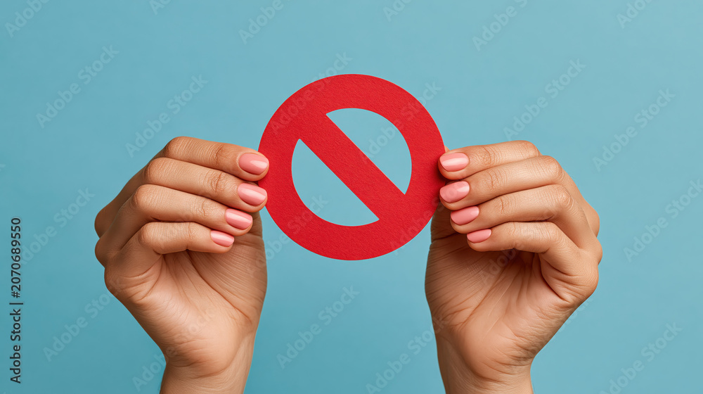 Fototapeta premium Close up of hands holding red prohibition sign for ban restriction warning stop message and simple safety communication