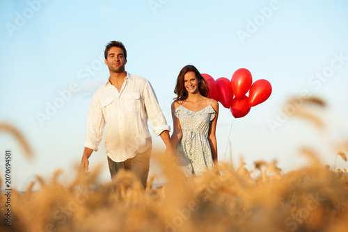 Foto Portrait, couple and holding hands in countryside with balloons, walk and bonding for anniversary