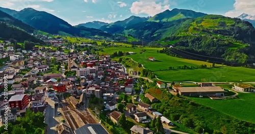 A Swiss town situated in the Alps and amidst green meadows. Establishing shot of Switzerland. Aerial view of Swiss