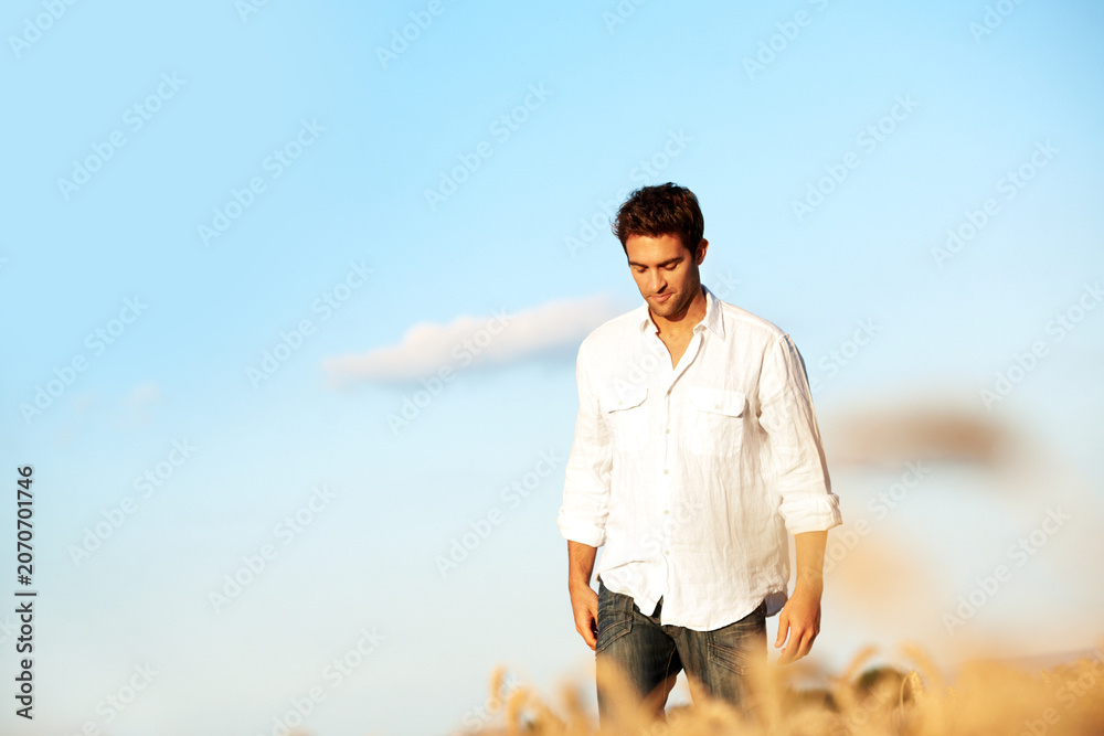 Obraz premium Thinking, walking and man at wheat field on holiday with peace, calm and space for sightseeing. Reflection, outdoor and person in countryside for trip, travel and vacation adventure in summer