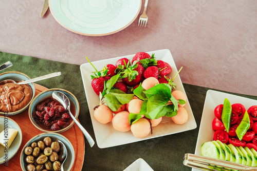 traditional turkish breakfast feast with rich variety on table photos series, fruit plate with strawberry and apricot, olives green and black, cut tomatoes, cucumbers