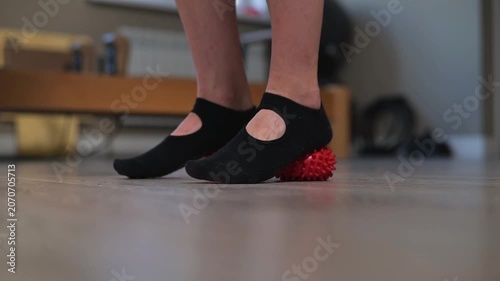 Close-up of person practicing leg stretching with massage balls during indoor Pilates workout