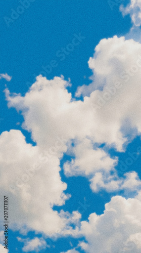 Fluffy clouds with grainy noise effect on vibrant blue background. Trendy vertical background template, cover, and wallpaper for social media stories.