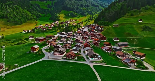 A Swiss town situated in the Alps and amidst green meadows. Establishing shot of Switzerland. Aerial view of Swiss