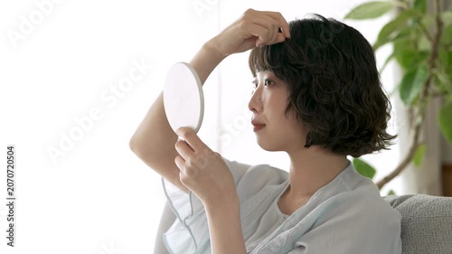 鏡を見ながら前髪を整える女性, Woman Adjusting Her Bangs While Looking in a Mirror
