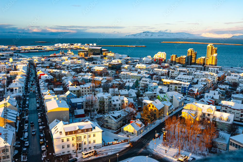 Obraz premium Winter aerial panorama of Reykjavík Iceland with snow covered streets colorful neighborhoods and the North Atlantic coastline viewed from above