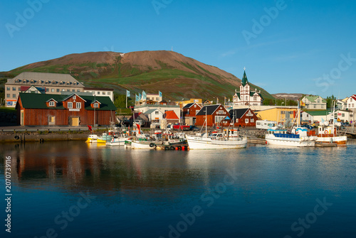 Fotografie Fishing boats in Húsavík Harbor Iceland with the iconic Húsavík Church colorful